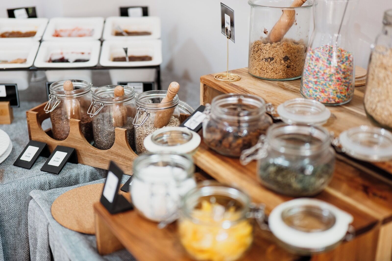A variety of jars and containers on a wooden table, likely for food or drink preparation.