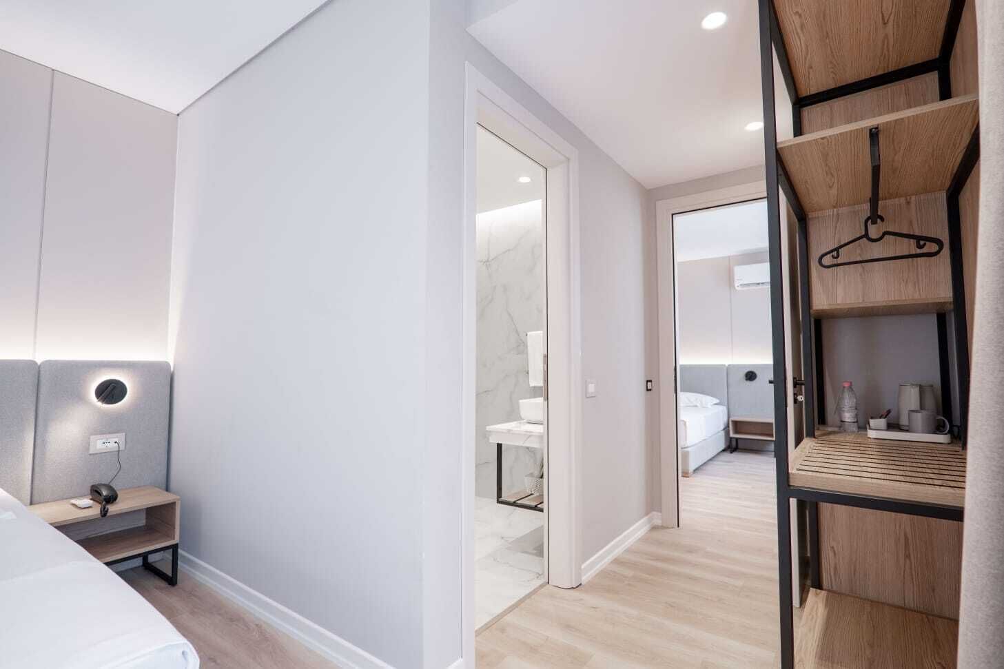 Un dormitorio moderno con cama, mesita de noche y lámpara de pared.