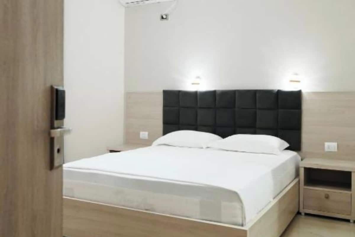 Un dormitorio moderno con cama, mesitas de noche y un velador.