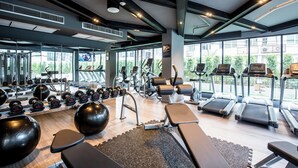 Un gimnasio moderno con diversos equipos de ejercicio, amplias ventanas y un diseño limpio y espacioso.