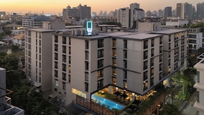 Un edificio alto con múltiples balcones, una piscina en la azotea y un horizonte urbano al fondo.