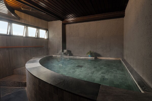 A spa area with a hot tub, wooden steps, and a window with curtains.