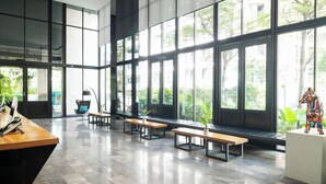 Un espacio interior amplio con ventanas grandes, bancos de madera y una mesa de recepción.
