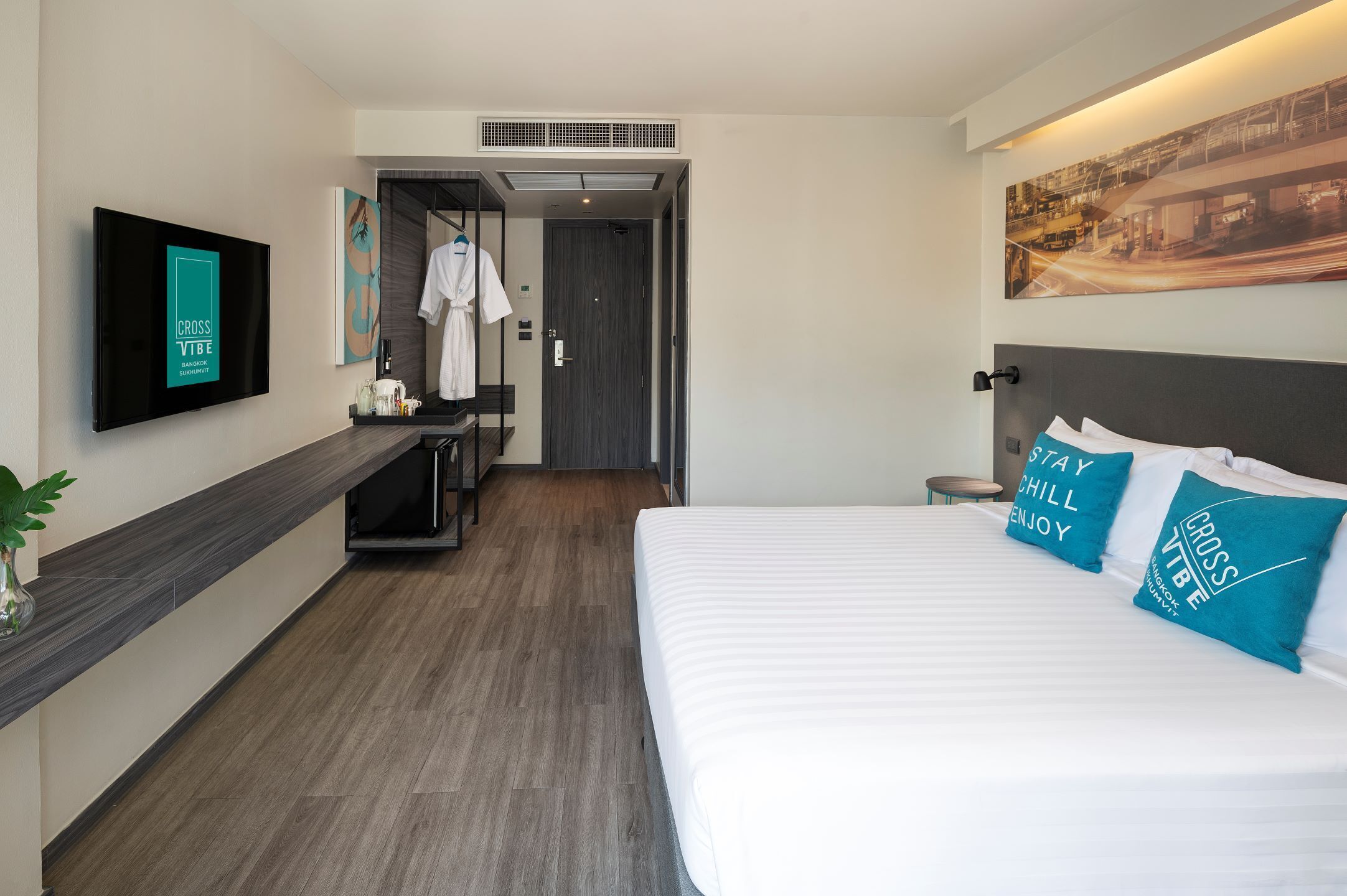 A modern hotel room with a bed, a TV, a desk, and a shower area.