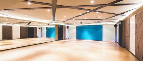 A spacious room with a wooden floor, large mirrors, and blue accent walls.