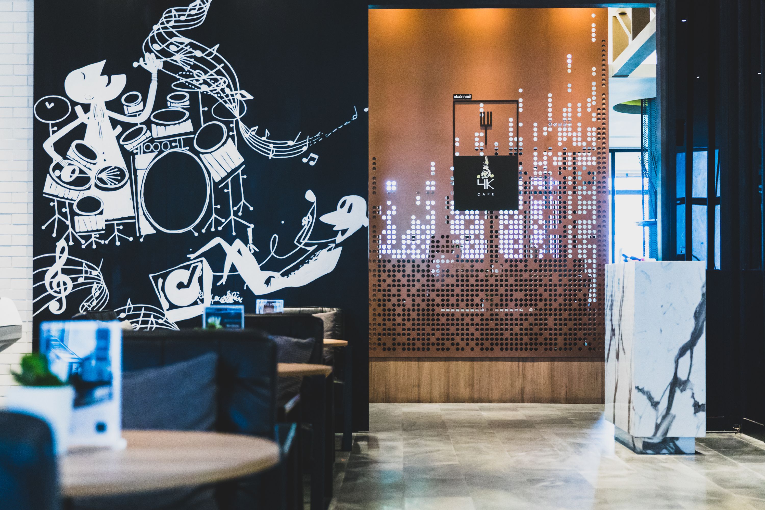 A modern interior with a black and white mural, a wooden partition with a perforated design, and a marble column.