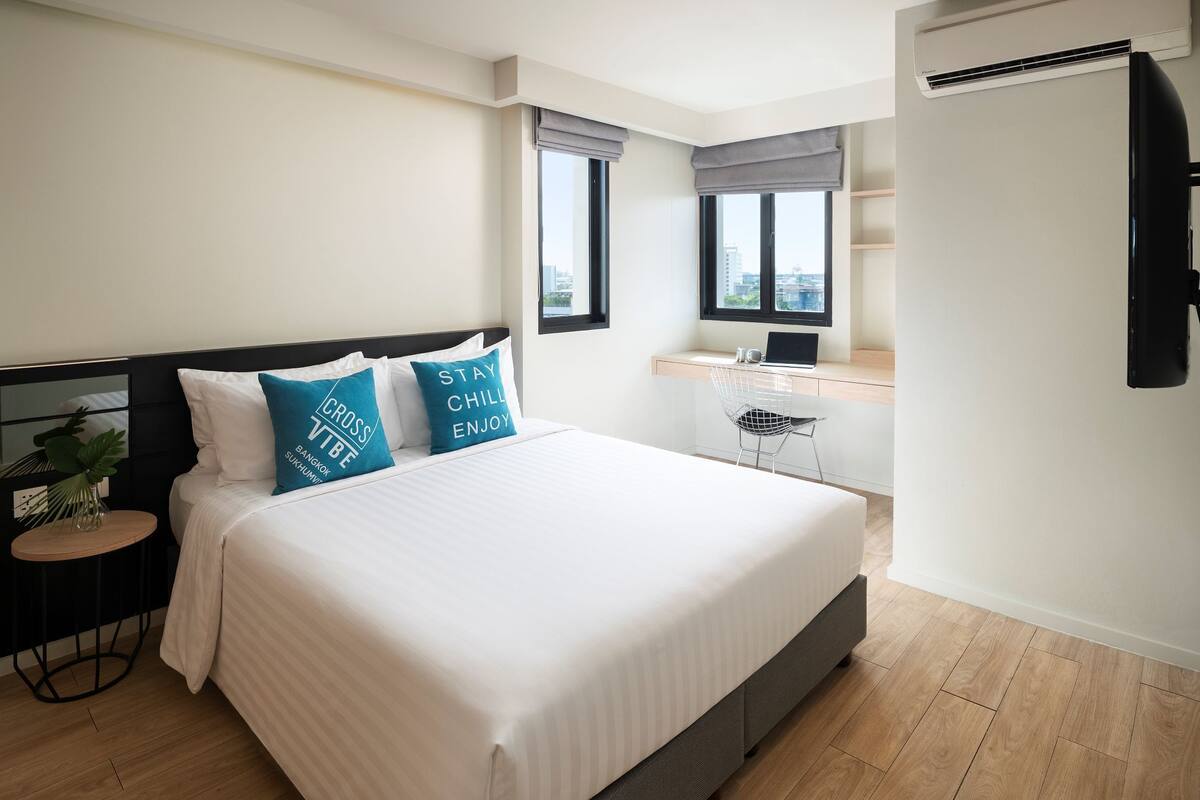 Ein modernes Hotelzimmer mit einem großen Bett, einem Schreibtisch und Blick auf die Stadt.