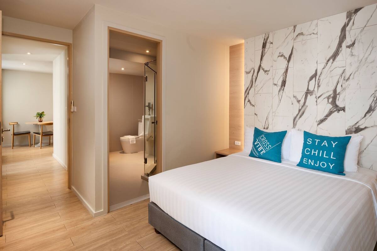 Ein Hotelzimmer mit einem großen Bett, einer Wand mit Marmorstruktur und zwei Kissen mit Aufdruck.
