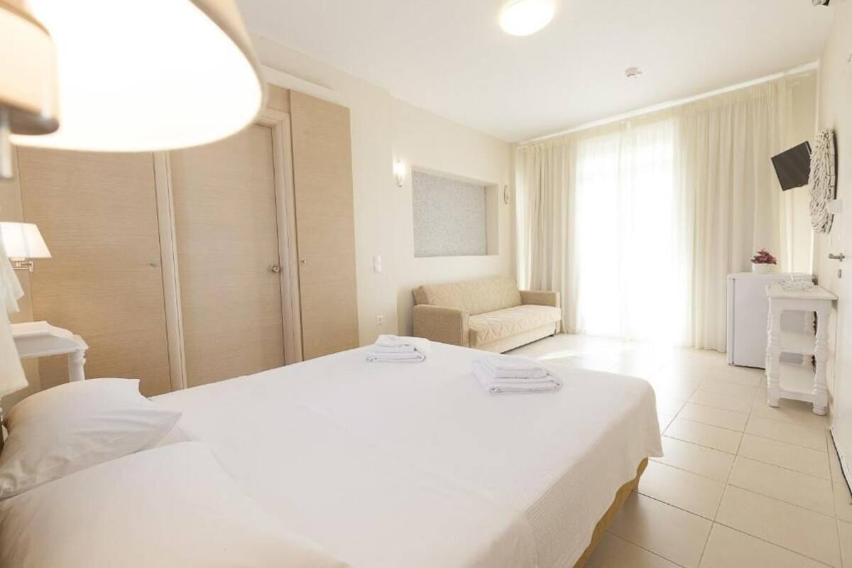 A hotel room with a bed, a sofa, a desk, and a mirror.