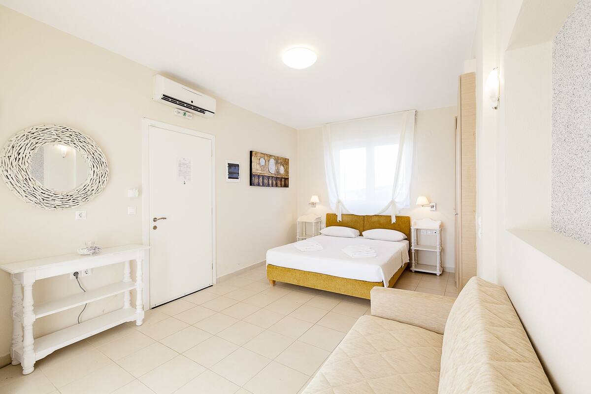 A bedroom with a bed, bedside tables, a console table, a mirror, and a door.