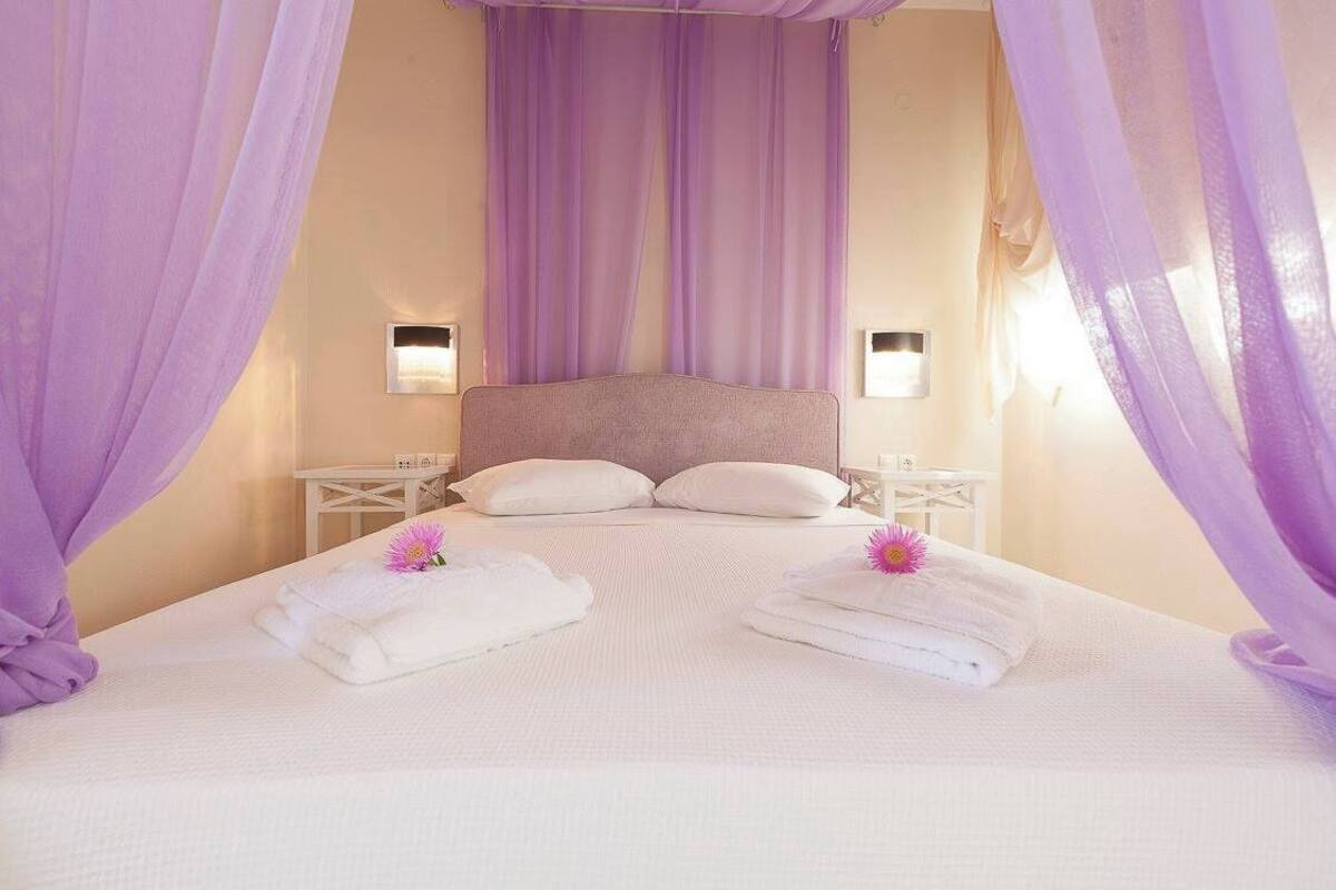 A bed with white linens, two pillows, and a canopy.