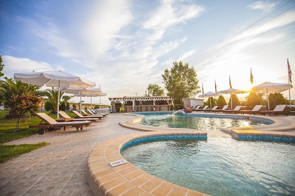 Una piscina al aire libre, sombrillas, sillones reclinables de piscina