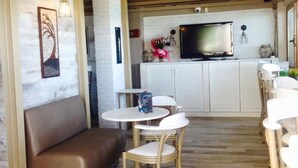 Una sala de estar moderna con un sofá, dos sillones, una mesita y un televisor al fondo.