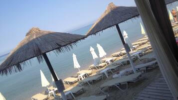 Na praia, espreguiçadeiras, guarda-sóis, bar na praia