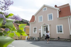 A two-story building with a red-tiled roof, a front entrance with steps, and a sign above the door. - Villa Evalotta Logi i Fjällbacka (Fjallbacka)