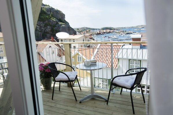 A balcony with two chairs and a small table, overlooking a marina and coastal town. - Villa Evalotta Logi i Fjällbacka (Fjallbacka)