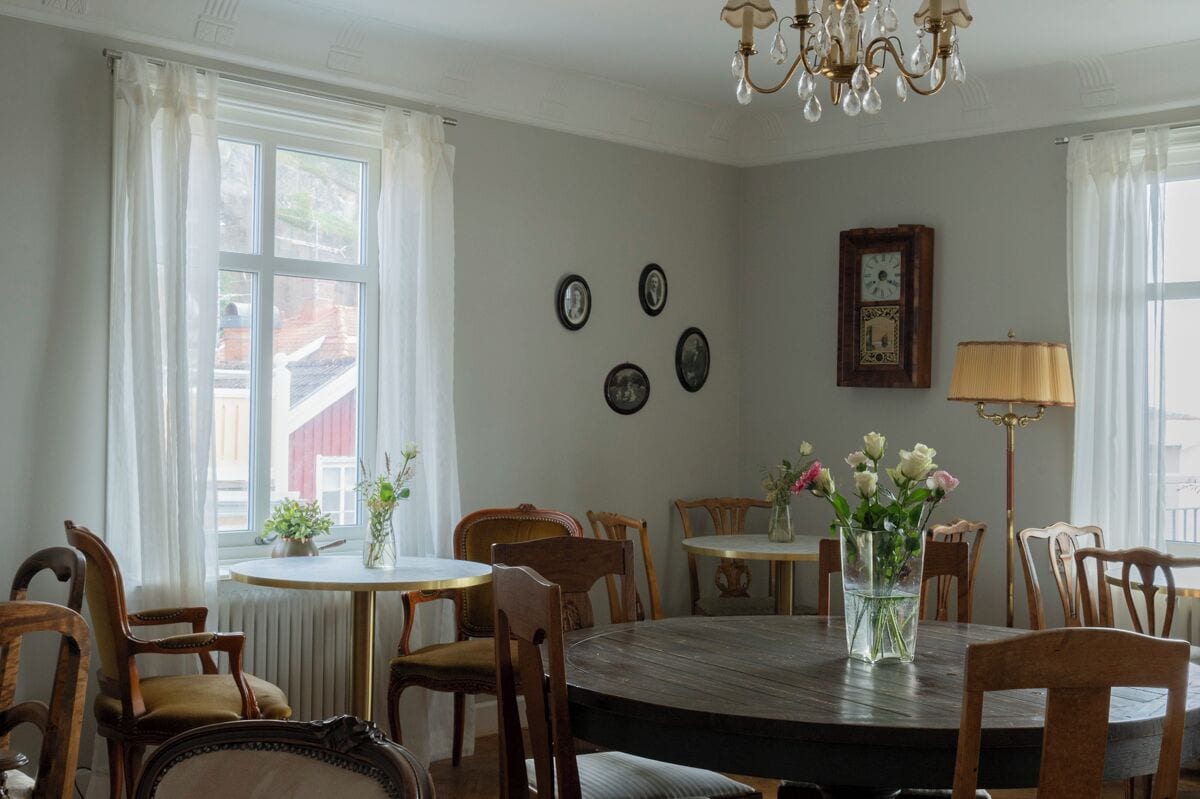 Ein Esszimmer mit rundem Tisch, Stühlen, einer Chandelierleuchtre und Wanduhren.