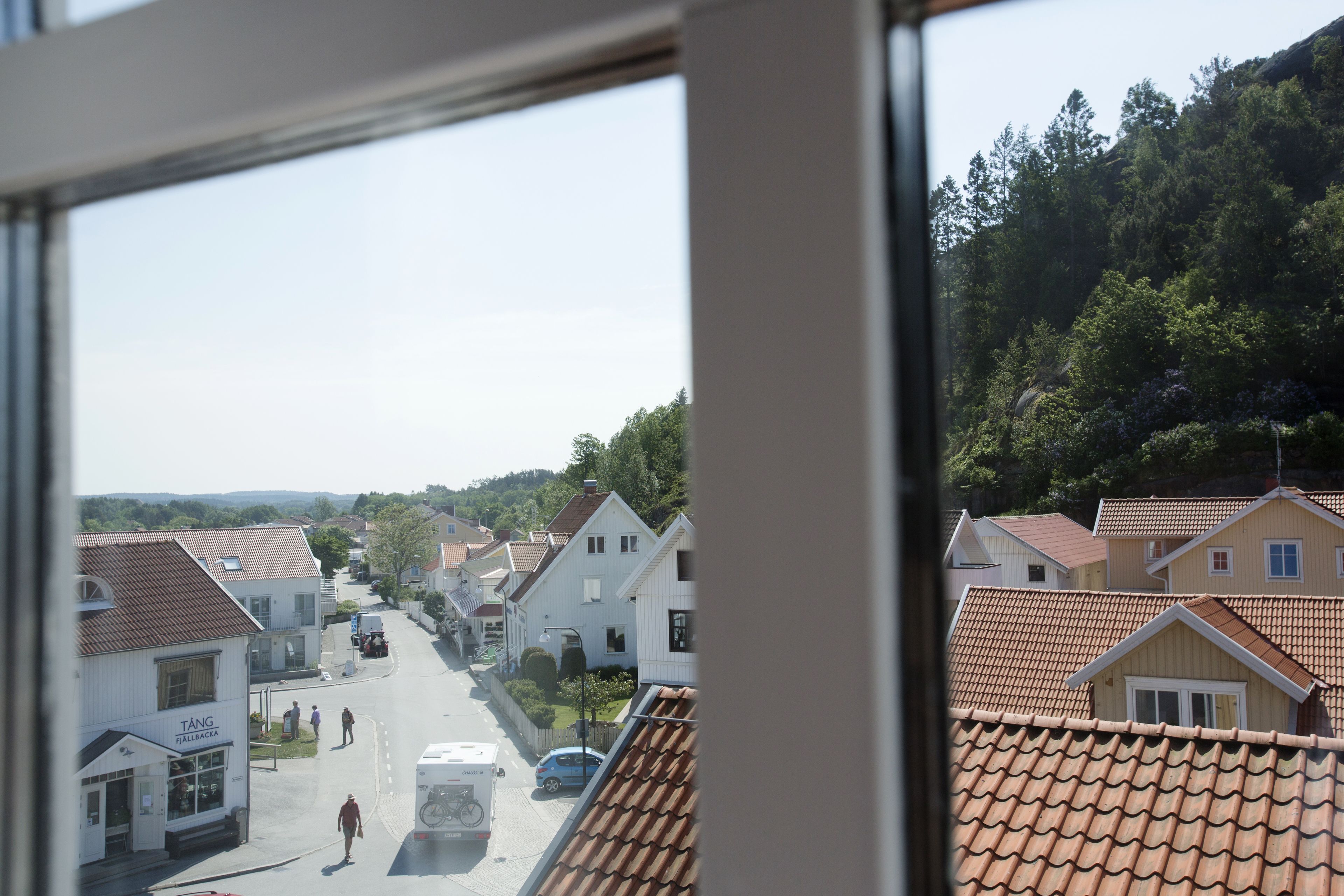 Straatbeeld met huizen, een heldere lucht en een glooiend landschap.