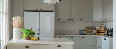 A modern kitchen with a two-door refrigerator, a built-in oven, a coffee maker, and a sink.