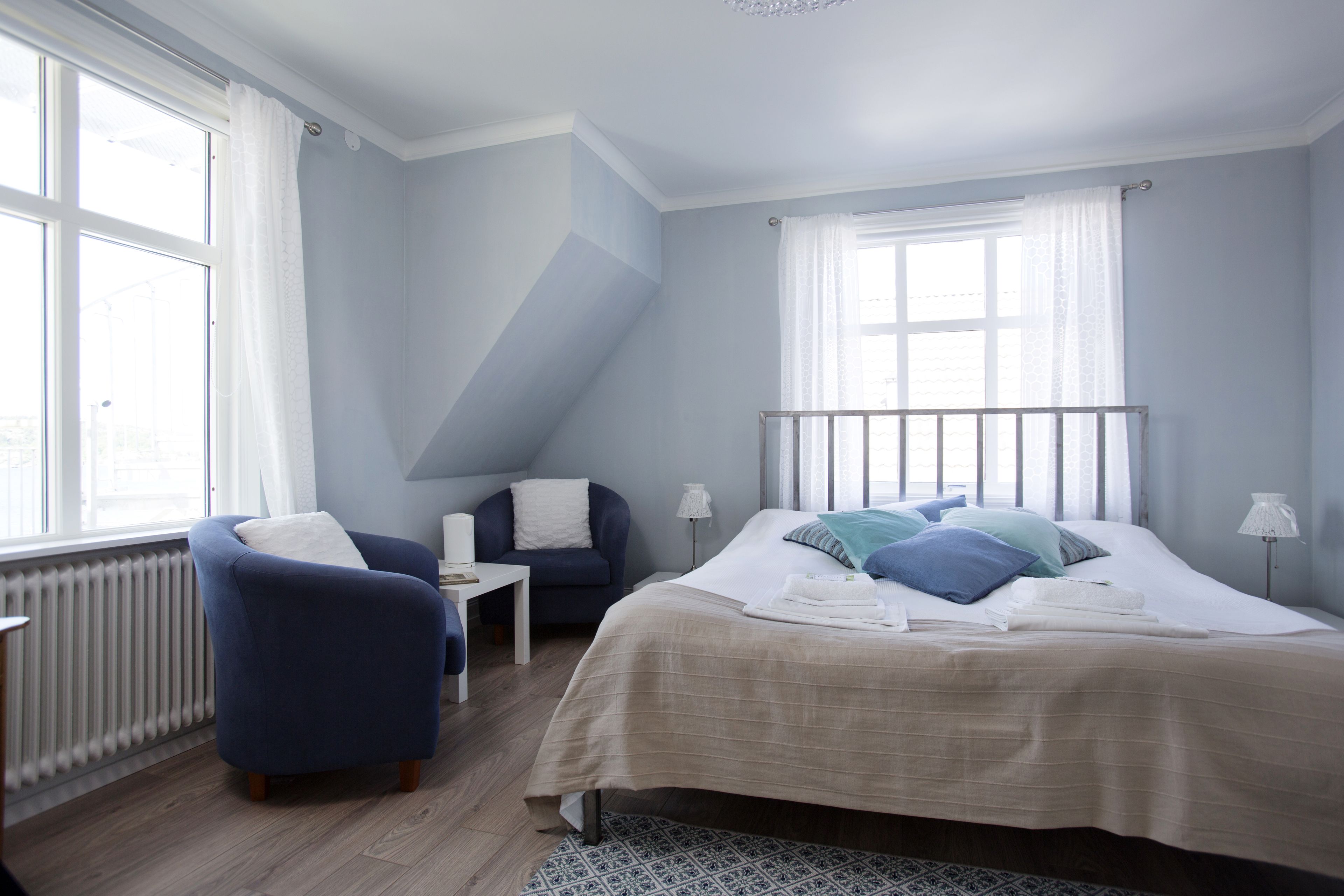 Een slaapkamer met een bed, twee stoelen, een kleine tafel en een radiator.