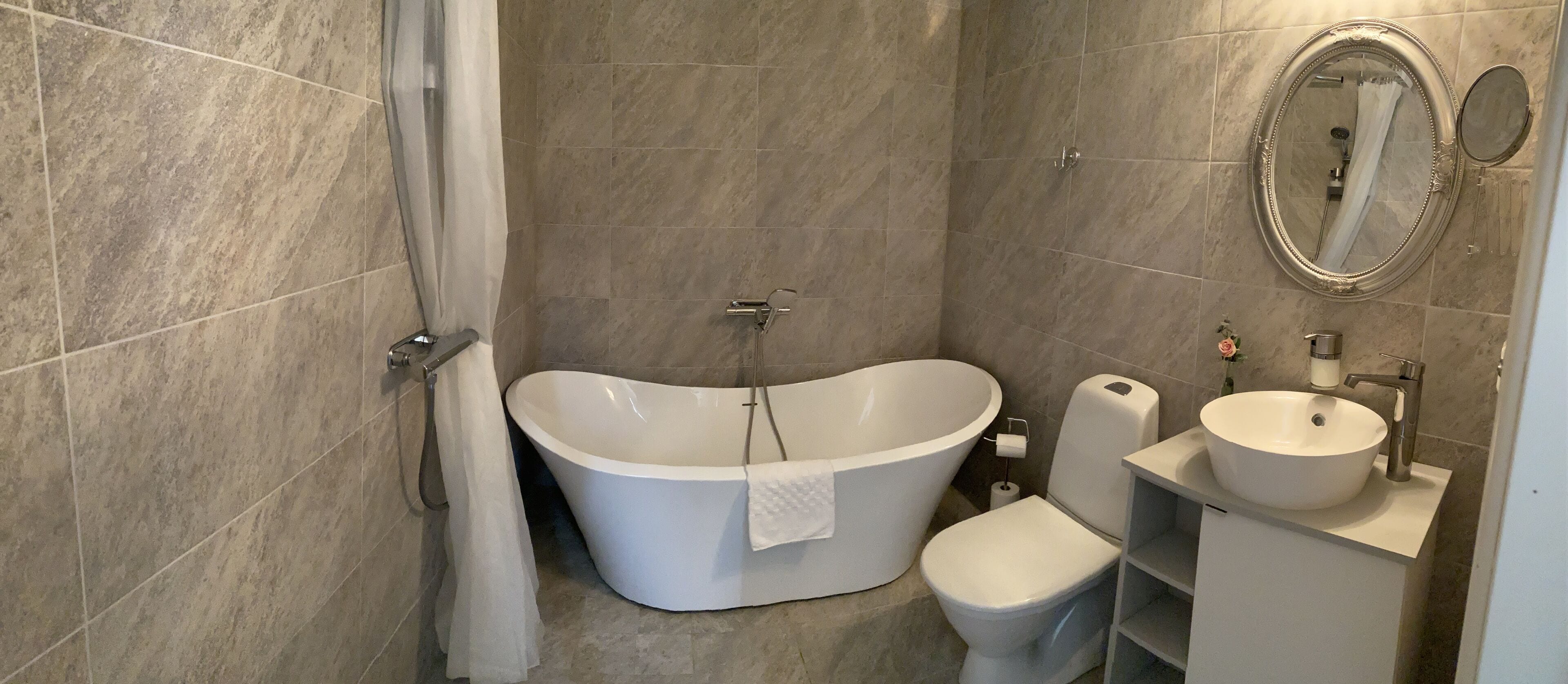 A bathroom with a freestanding bathtub, a toilet, and a sink with a mirror.