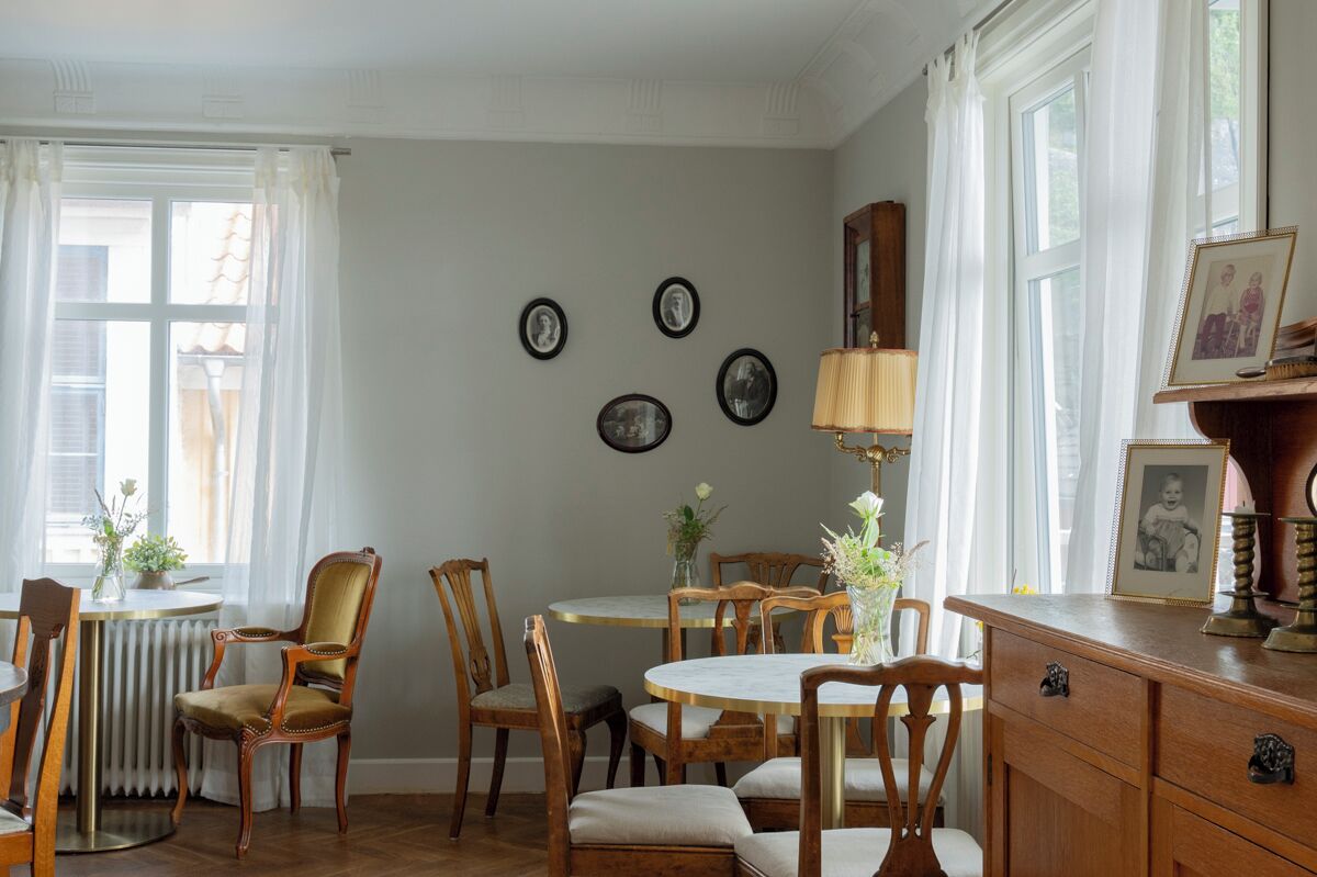 Uma sala de jantar com uma mesa redonda, cadeiras, um radiador e um abajur.