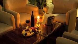 A cozy seating area with two armchairs, a wooden table with a bottle of wine, glasses, and a fruit platter.
