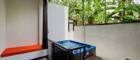 A small outdoor area with a hot tub, a bench, and a table.