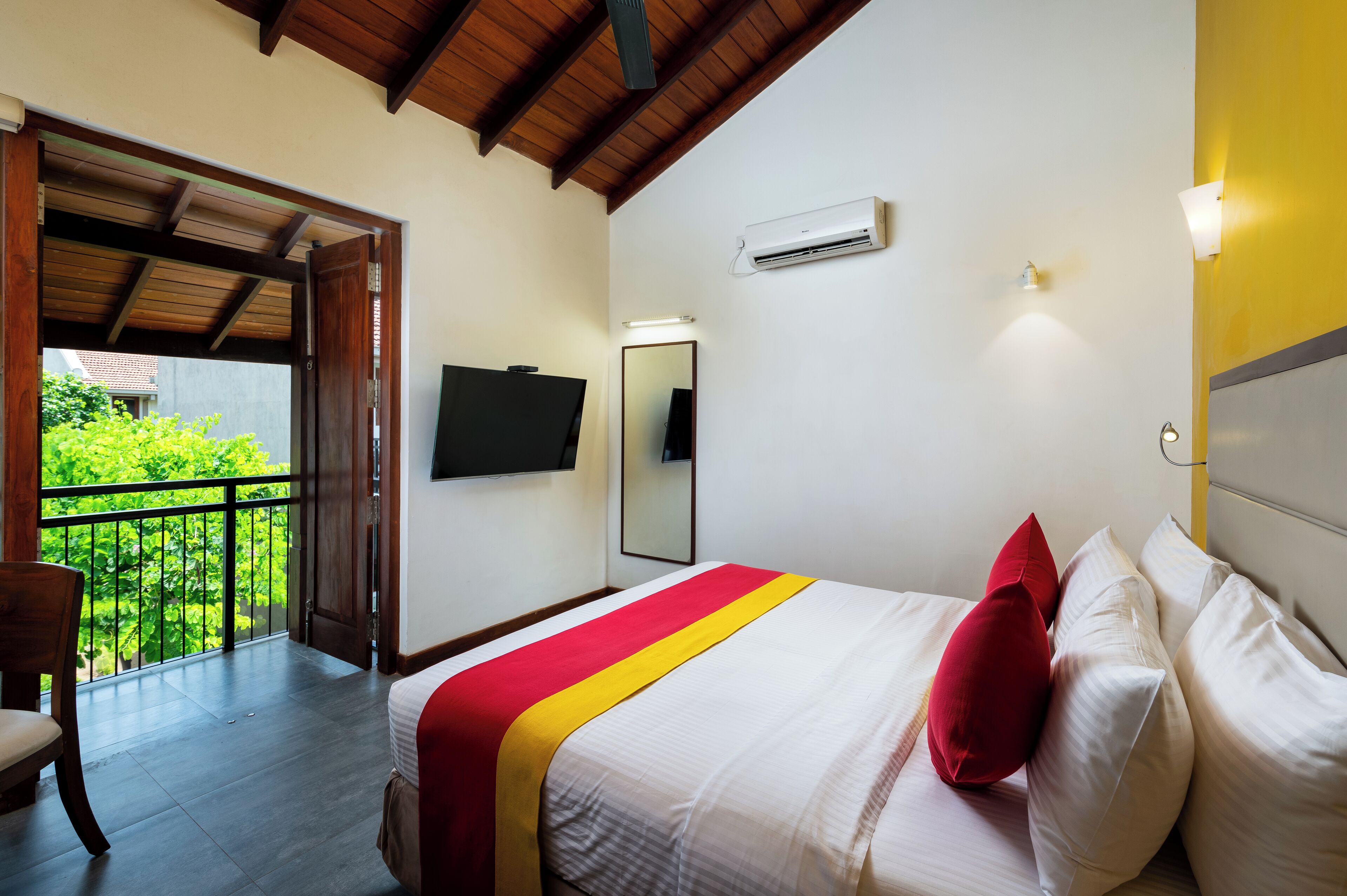A hotel room with a bed, a TV, a balcony, and an air conditioning unit.