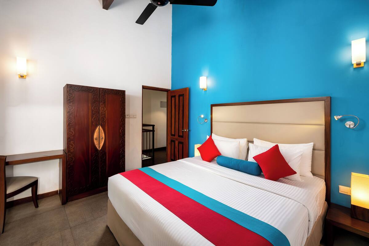 A hotel room with a bed, a desk, and a wardrobe.