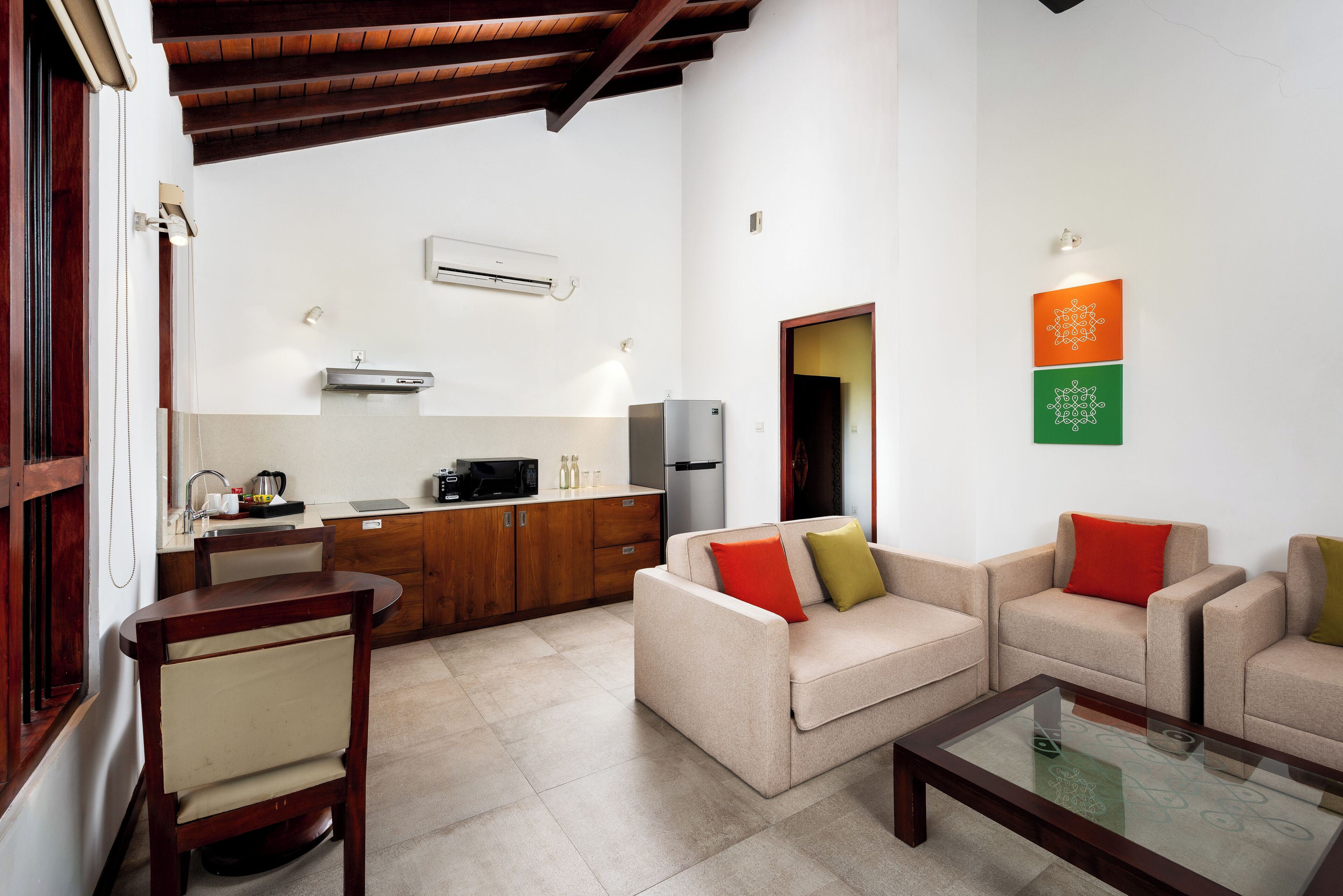 Un espacio habitable compacto con kitchenette, un conjunto de sofás y una mesa de centro de vidrio.