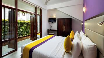 A hotel room with a bed, a TV, a desk, and a view of the outside.