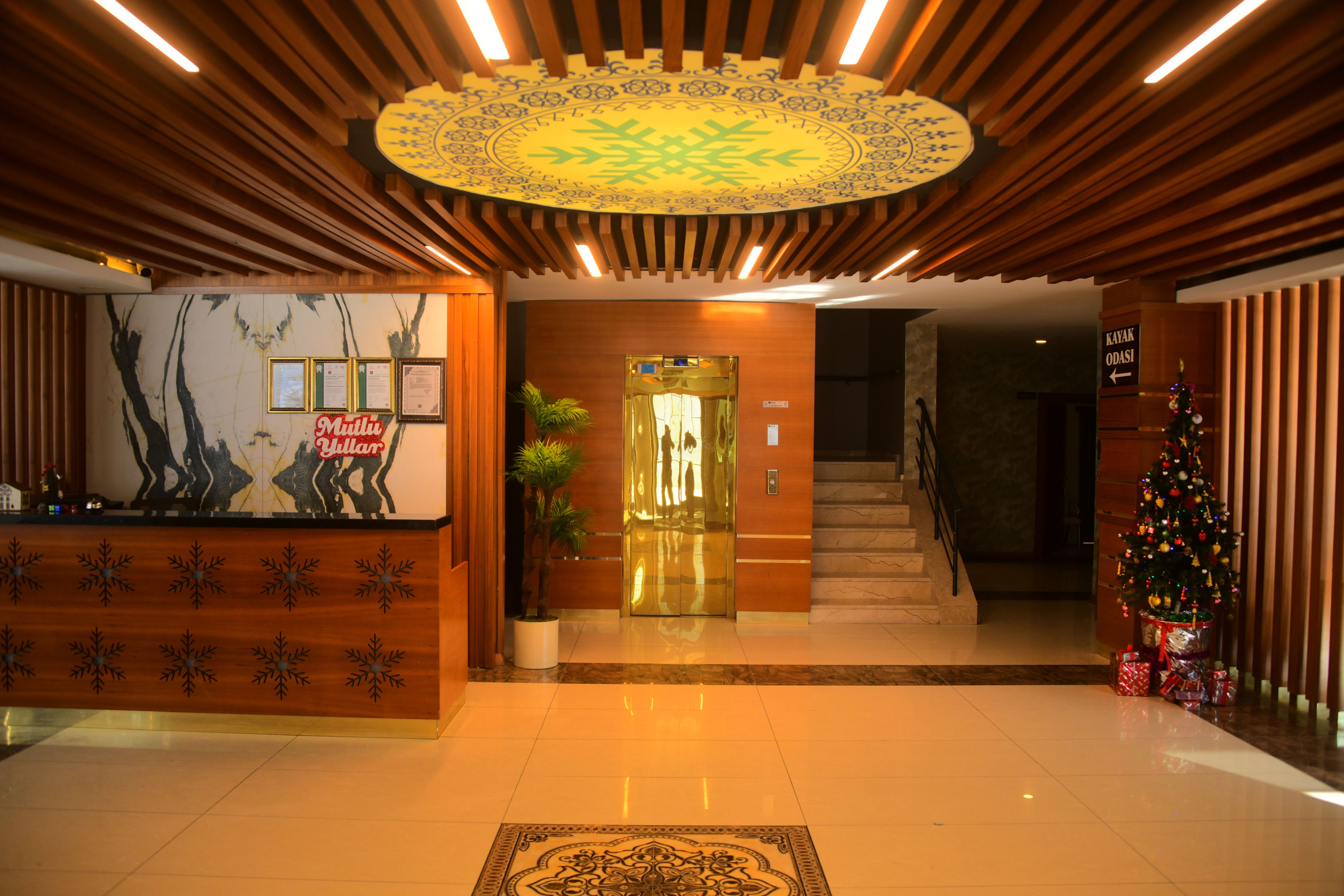 Zona de recepción con mostrador de madera, un árbol de Navidad y una escalera que conduce a los pisos superiores.
