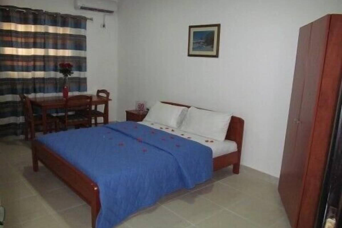 Une chambre à coucher avec un lit, une chaise, une petite table et un tableau accroché au mur.