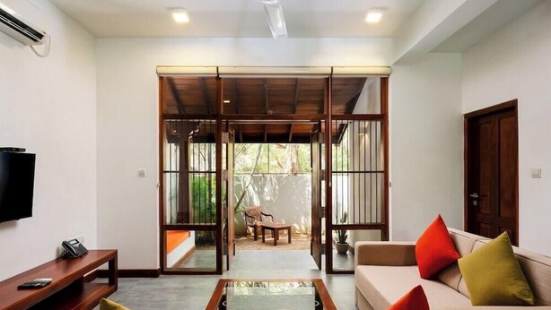 A modern living room with a sofa, coffee table, and a TV on a stand. - The Thinnai Hotel (Jaffna)