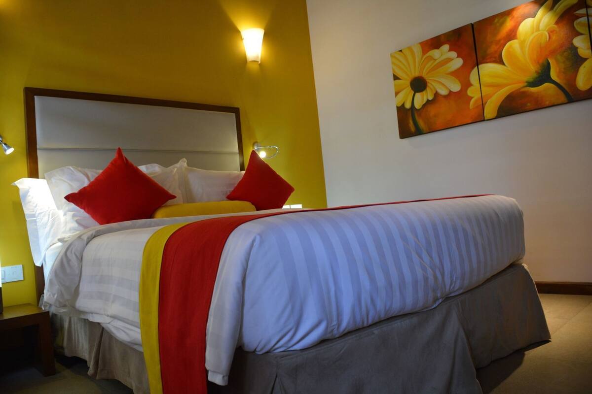 A bed with red and white pillows, a yellow and white striped blanket, and a red and white bed skirt.