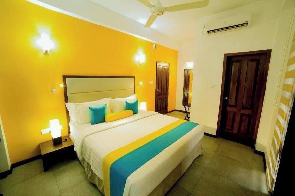 A hotel room with a bed, nightstands, a ceiling fan, and an air conditioning unit.