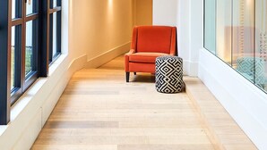 Un interior moderno con suelo de madera, una silla roja y un otomano estampado.