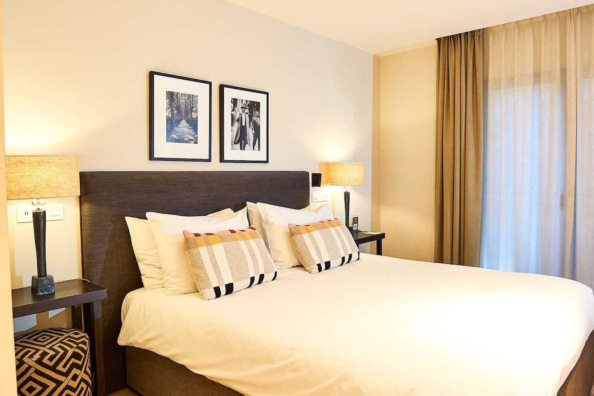 A hotel room with a large bed, two bedside tables with lamps, and two framed pictures on the wall.