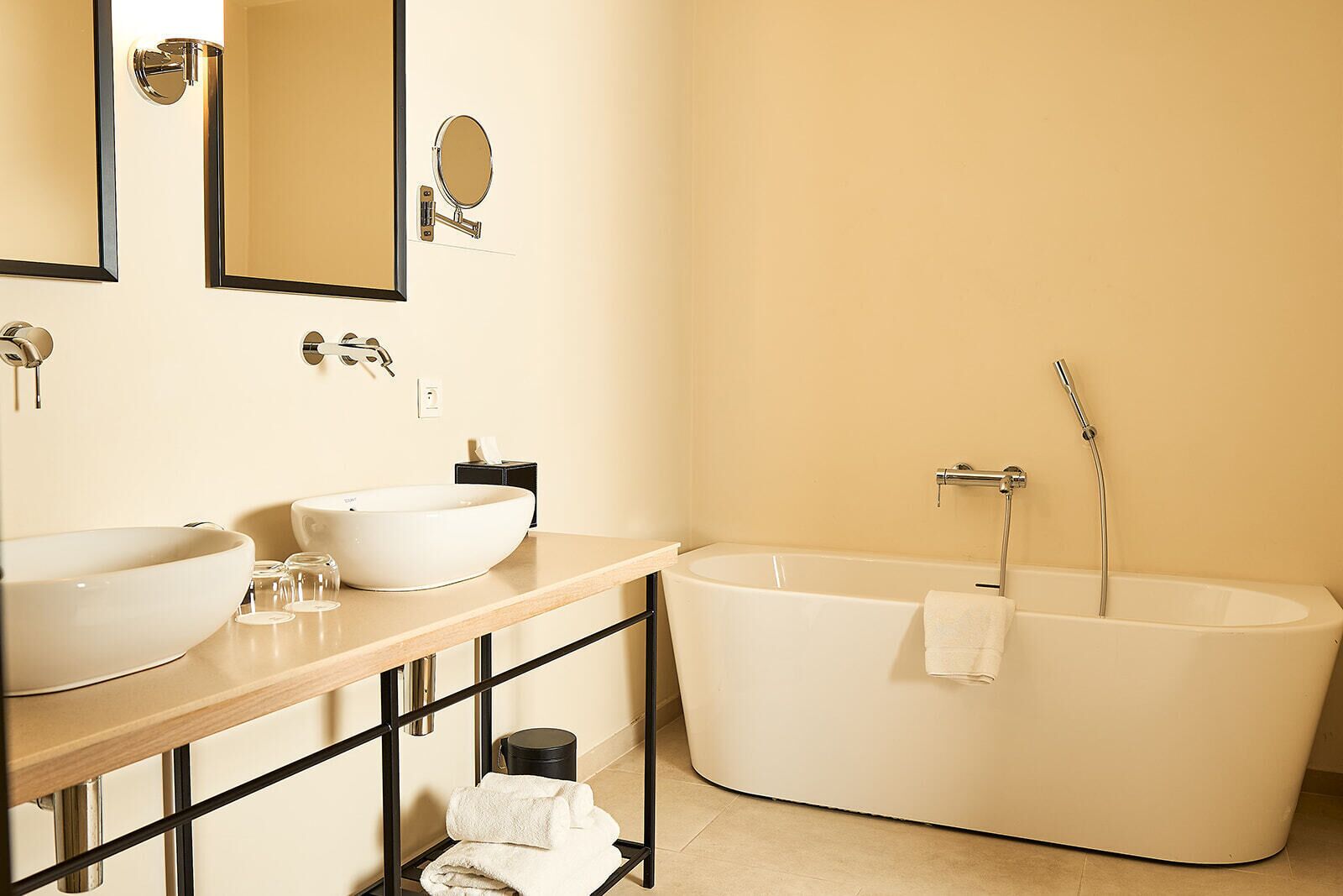 Une salle de bain moderne avec deux lavabos, une grande baignoire et un miroir.