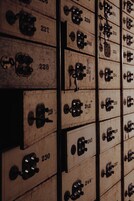 Una hilera de cajas de madera con cierres metálicos, cada una con un número.