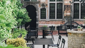 Un patio con un edificio de ladrillo, asientos exteriores y un pilar de piedra.