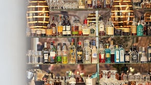 Zona de bar con estantes llenos de botellas de licores y vasos.