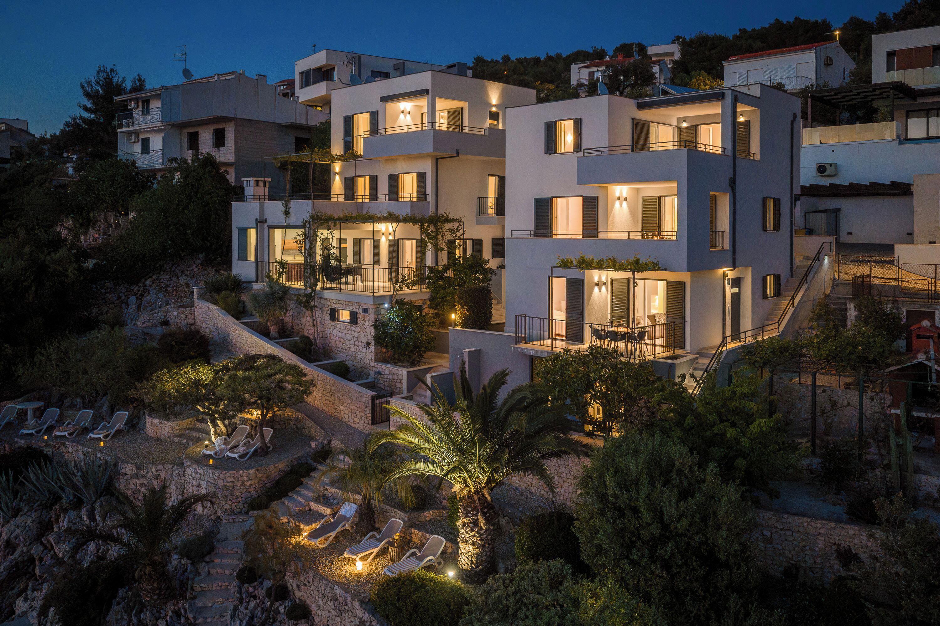 Un edificio residencial de varios pisos con balcones, mobiliario exterior y un sendero de piedra.