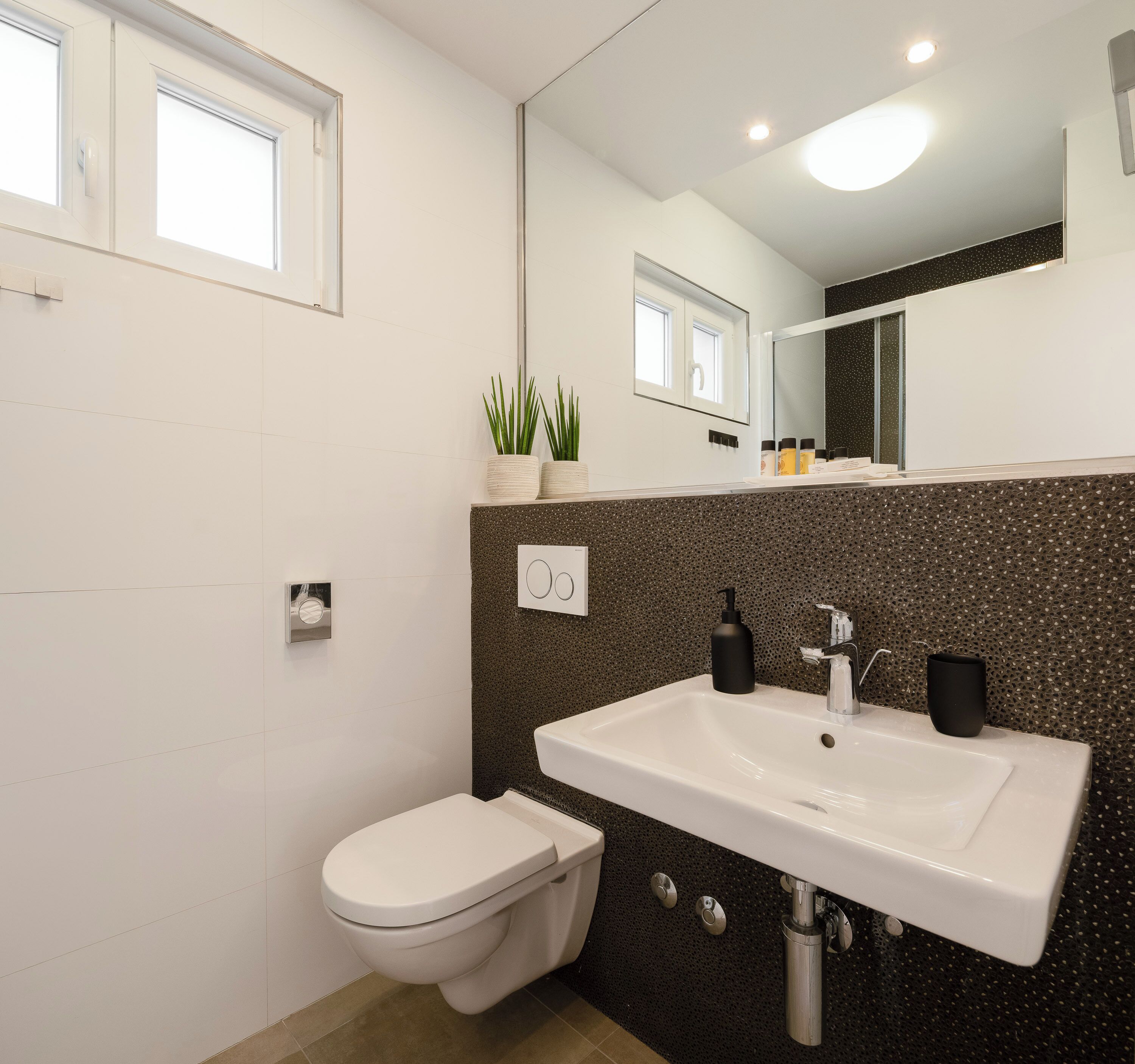 Une salle de bain moderne avec des toilettes, un lavabo et un miroir.
