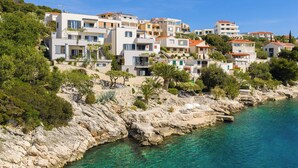A coastal residential area with modern buildings, clear blue water, and rocky terrain. - Villa Lavanda Deluxe (Rogoznica)