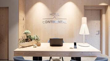 Habitación de hotel con pared de madera, un escritorio con una computadora portátil, un teléfono móvil y una lámpara.