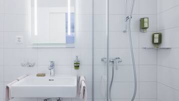 A modern bathroom with a white sink, mirror, and shower.