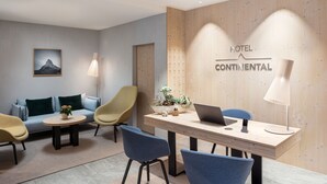 Un vestíbulo moderno de hotel con un mostrador de recepción de madera, un sofá, dos sillones, una pequeña mesa con una planta y un cartel en la pared que dice "HOTEL CONTINENTAL".