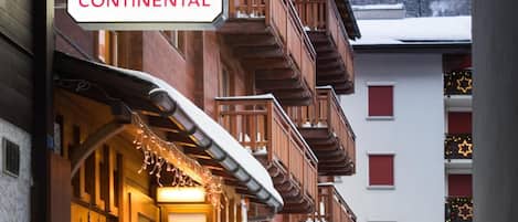 A hotel building with a sign reading 'HOTEL CONTINENTAL' and another sign for 'ALPHUBEL HOTEL' in the background.